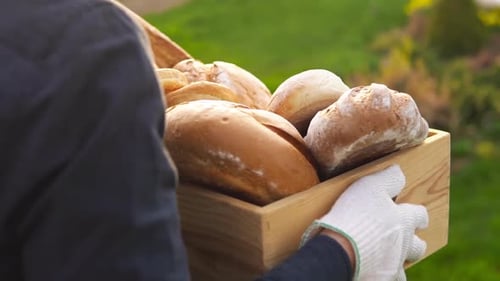 Woman carries bread in a field. Assorted bread in a basket.