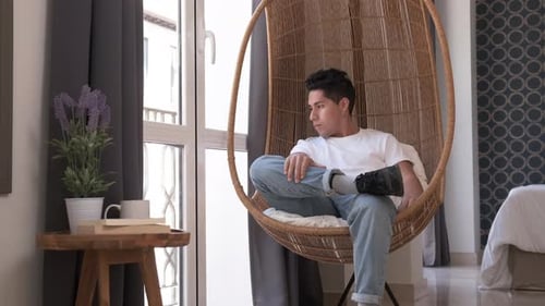 Young Adult Relaxing in Hanging Chair at Home