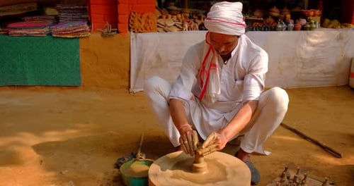 Potier indien au travail : lancer le volant du potier et façonner un récipient en céramique et des articles en argile : pot