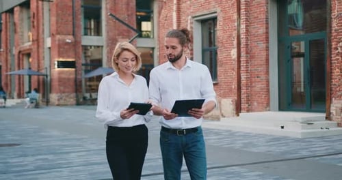 Business Partners Man and Woman, Business Partners Walking the Street Talking and Using Tablet