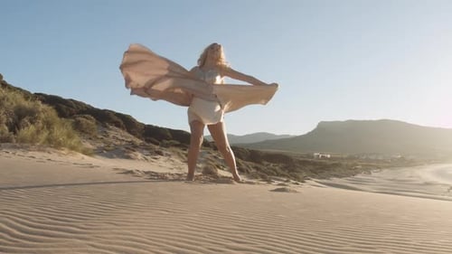 Woman In Gold Dress Dancing On Sandy Beach