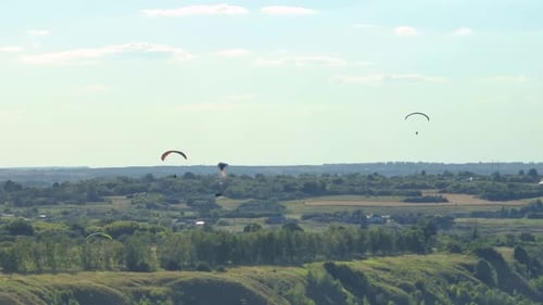 Aerial Footage of Flying Paragliders Against Green Hills and Sky