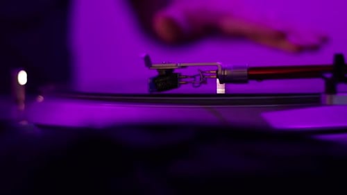 Una aguja de tocadiscos vintage hace girar un disco distorsionado y distorsionado bajo una luz negra mientras un disco