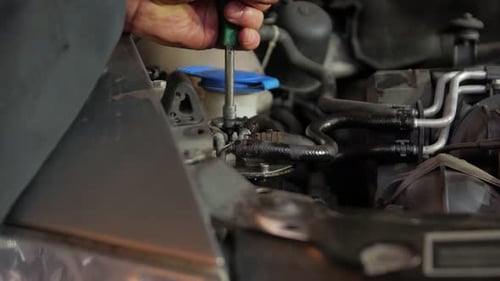 Mechanic Repairing Car Engine with Screwdriver Close-Up