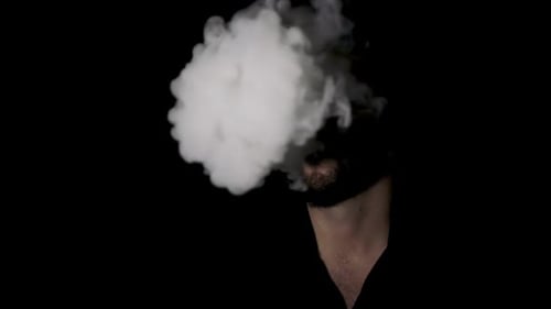 Man Exhaling White Smoke on a Black Background