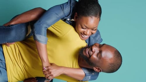 Playful Couple Piggybacking and Embracing in Studio