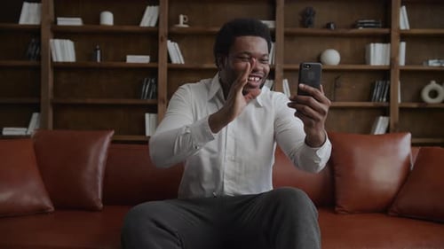 Adult Man Greeting During a Video Conference Call Using Smart Phone in His Loft Officce