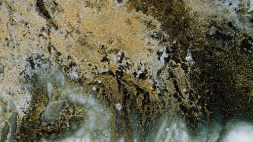 La peinture blanche s'étale sur un fond noir et doré en mouvement