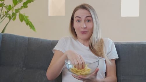 Woman Watching TV and Eating Chips on Sofa