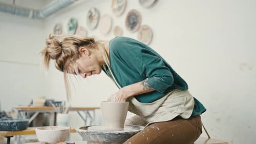 Female Potter Shaping Clay on Wheel in Studio