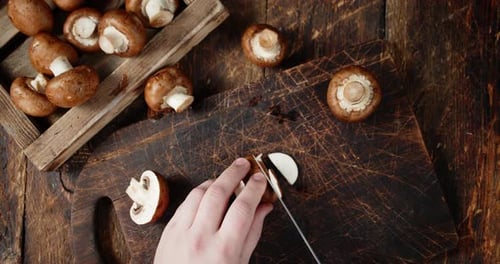 Hand Cuts Fresh Mushrooms on Cutting Board