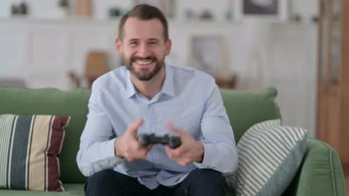 Man Plays Video Games at Home, Smiling