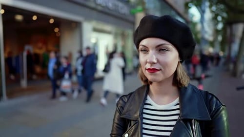 Portrait of Trendy European Woman in Hat Standing on Busy City Street