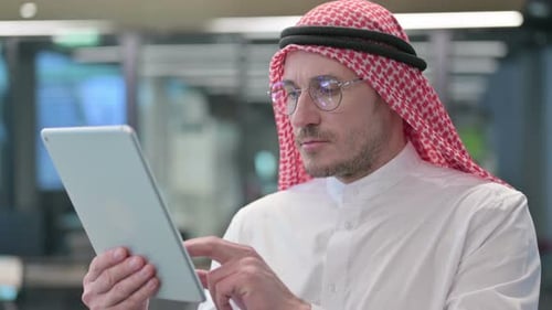Man in Traditional Dress Using Tablet in Office
