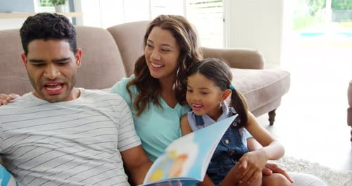 Happy family reading book in living room