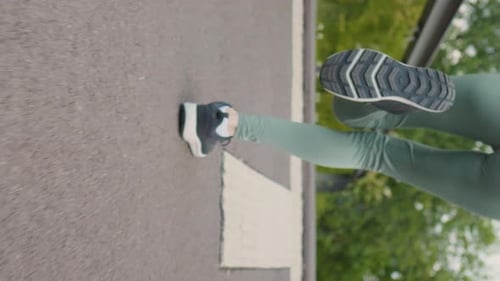 Vertical Screen Woman running in the park, legs close-up