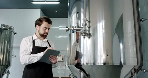 Beer Production. Brewery Worker Checking Beverage Equipment at Brewery or Beer Plant.