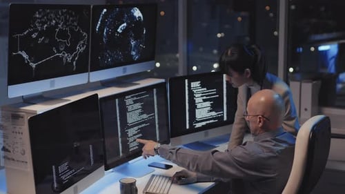 Two Colleagues Working on Code at Night