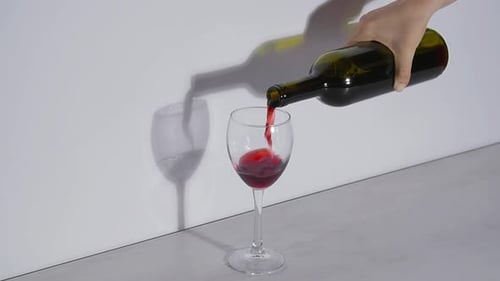 Plan conceptuel, verser du vin rouge dans un verre sur fond gris