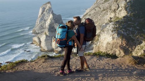 Couple of Backpack Tourists Standing at Cliff