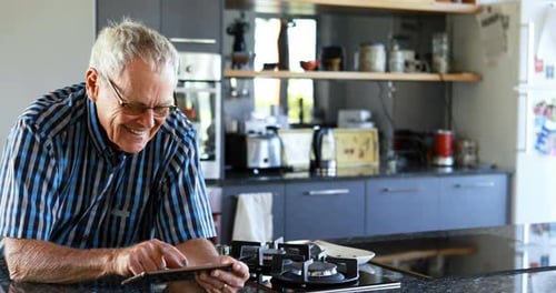Senior Man Using Tablet Device in Modern Kitchen