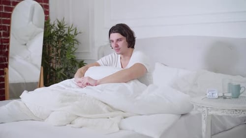 Man Wakes Up and Stretches in Bed