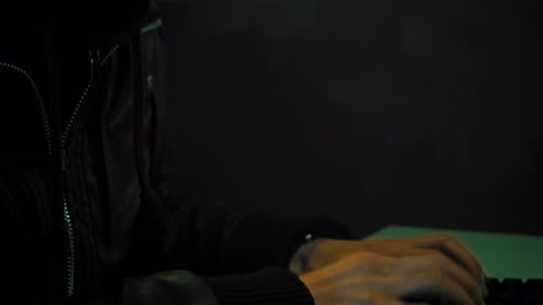 Person in Hooded Jacket Typing at Night