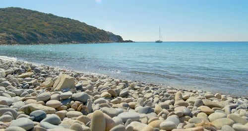 Wellenlandung am Stone Beach. Yacht am Horizont. Klares blaues Wasser