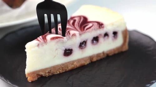 Cutting a Slice of Cherry Cheesecake with a Fork