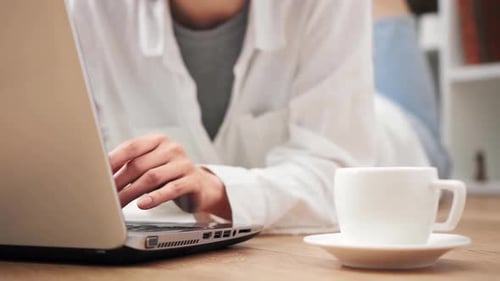 Woman Working on Laptop with Coffee at Home