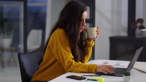 Fokussierte Geschäftsfrau arbeitet Laptop im Büro. Schöne Frau trinkt Tee
