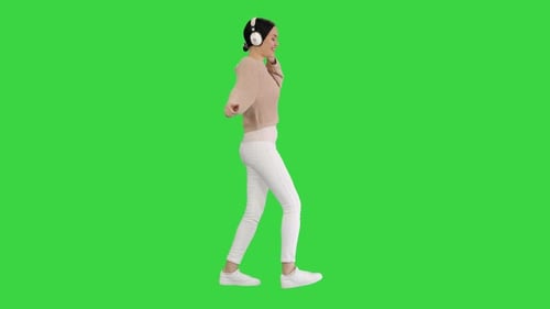 Happy Emotional Girl Listening To Music Via White Headphones and Walking on a Green Screen, Chroma