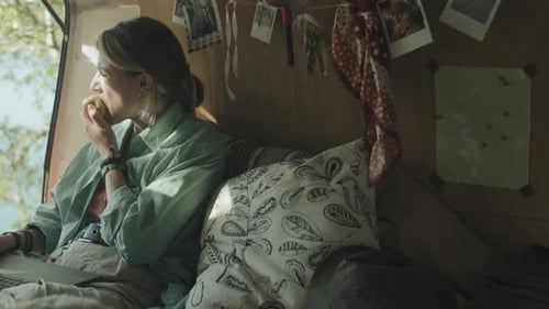 Woman Using Laptop in Camper Eating Apple