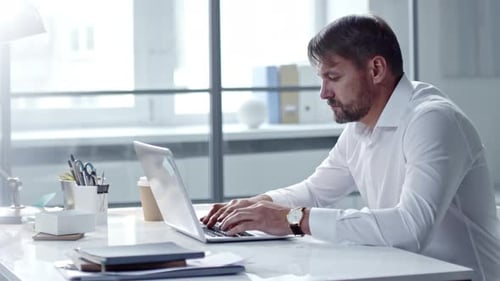 Man Typing on Laptop in Bright Office