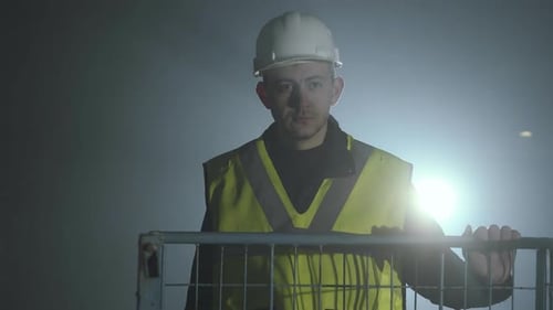 Man in Hardhat Leaning on Railing at Night