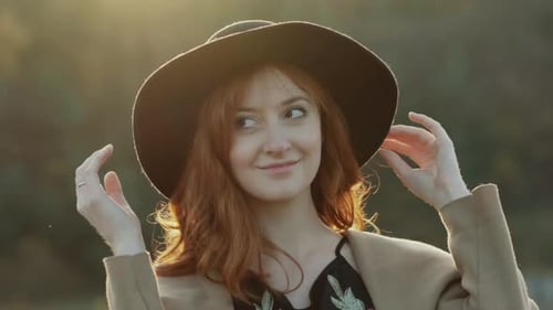 Woman Putting on Hat in Golden Sunset Light