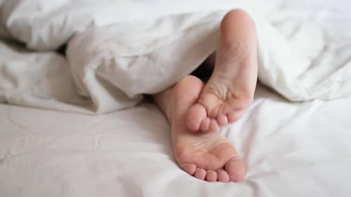 Feet Moving Under White Bed Sheets, Close Up
