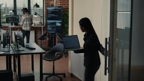 Desenvolvedor de software segurando laptop com algoritmo de código fonte entrando no escritório da agência de