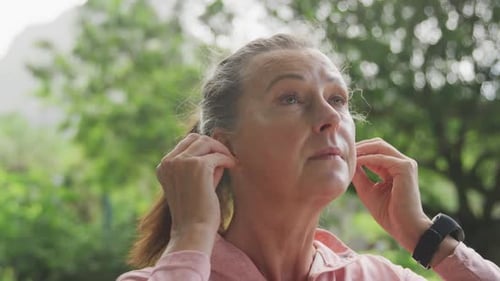 Senior woman using wireless earphones in the park