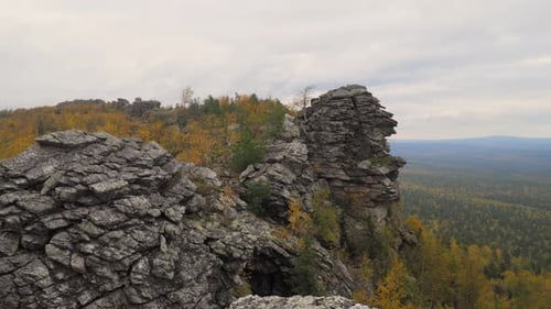 Rocky Mountain Among Yellow Colorful Tree Forest in Gloomy Overcast Weather in Autumn