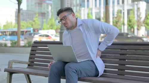 Man Works on Laptop, Suffers From Back Pain