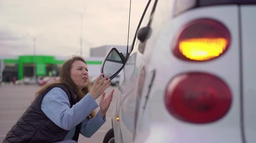 Woman Adjusts Mirror on Car in Parking Lot
