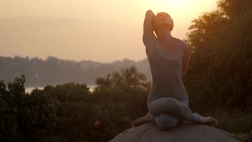 Un professeur de yoga fait du gomukhasana sur des rochers et des arbres au Ralenti