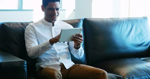 Man Relaxing with Tablet on a Black Couch