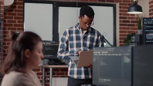 Portrait of African American Software Developer Holding Laptop Looking Up and Smiling