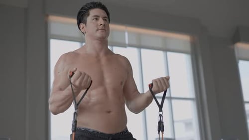 Muscular Man Exercising with Resistance Bands in Gym