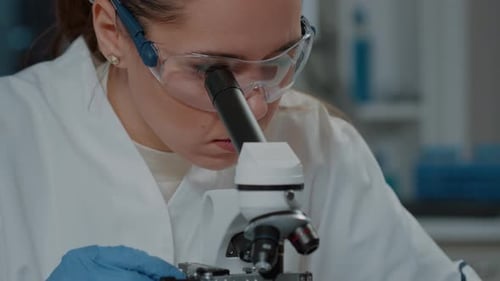 Scientist Looking Through Microscopic Lens to Work on Experiment