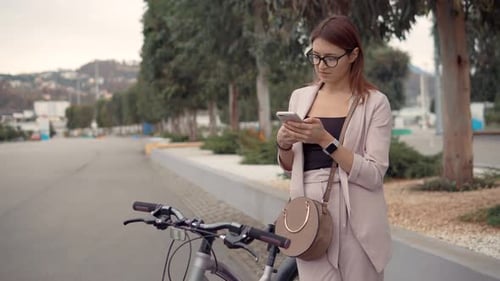 Woman Using Phone with Bicycle in Urban Setting