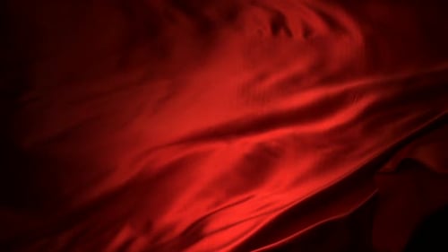 Red Fabric Rippling Against Black Background