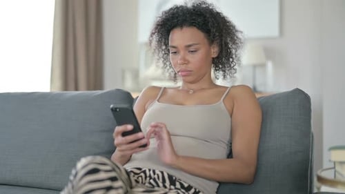 Woman Using Smartphone on Couch in Living Room